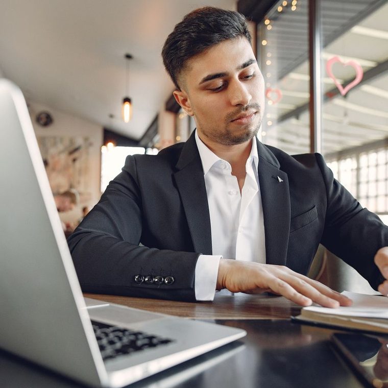 A student preparing for an exam with his notes and laptop