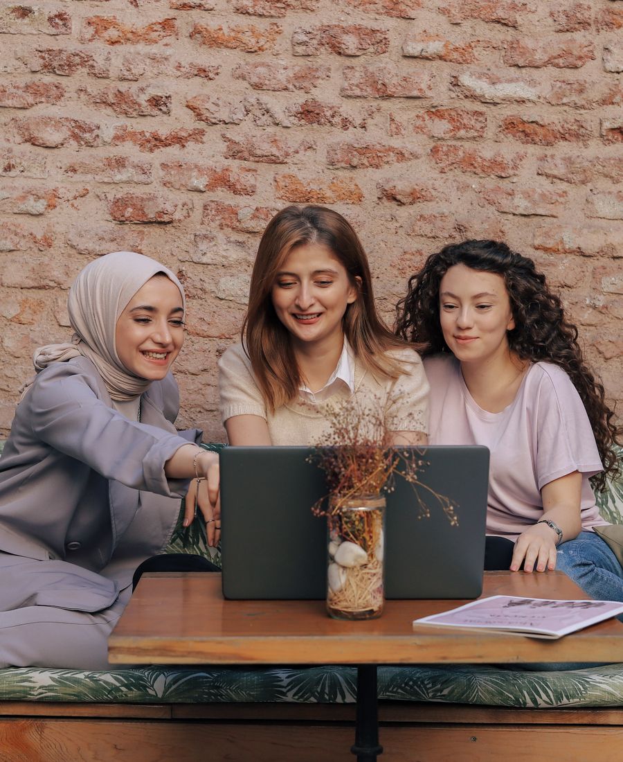 Three friends chatting around a laptop