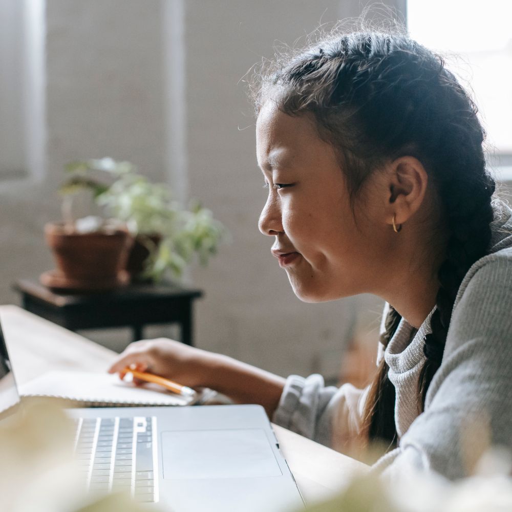 A smiling girl joining an online lesson on her laptop